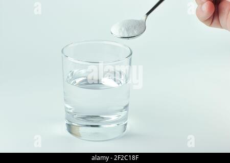 Spoon of baking soda and glass of water. Spoon of baking soda and glass of water. Baking soda, bread soda, cooking soda, bicarbonate of soda. Stock Photo