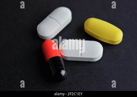 Tablets and capsule on black background. Medication concept. Stock Photo