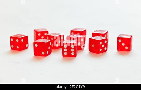 Ten red translucent craps dices on white board showing different numbers Stock Photo