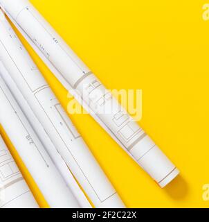 Construction project blueprints concept. Architecture drawings rolls on yellow color background, top view. Architect engineer office, copy space, temp Stock Photo