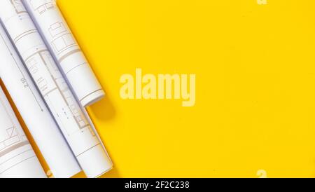 Construction project blueprints concept. Architecture drawings rolls on yellow color background, top view. Architect engineer office, copy space, temp Stock Photo