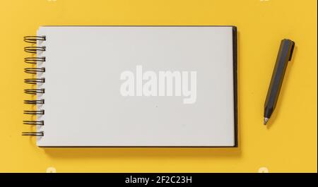 Blank notepad and architect pencil on yellow color background, top view. Opened paper spiral notebook, engineer construction design, draft and sketch Stock Photo
