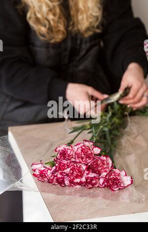 Woman makes a funeral bouquet of carnations Stock Photo