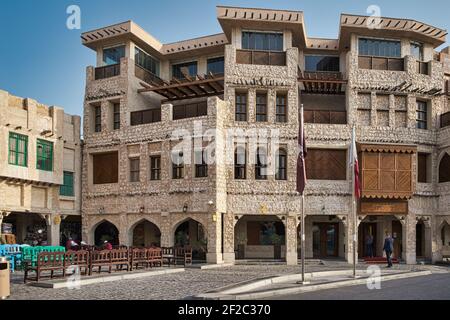 Souq waqif in Doha Qatar daylight view showing traditional Arabic architecture , Qatar flag and people in the street Stock Photo