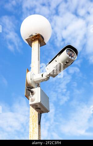Surveillance CCTV camera mounted on the post against the blue sky Stock Photo