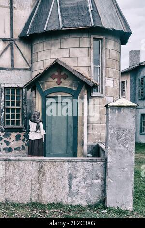 A woman parishioner in a headscarf is facing the door of a vintage Church Stock Photo