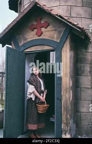 Portrait of a woman in medieval dress at the door of an old European Church, clothes on Halloween 18-19th century Stock Photo