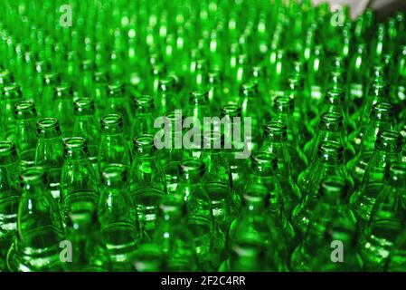 Rows of green glass bottles on the conveyor close-up. Industrial brewery Stock Photo