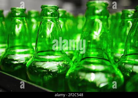 Automated conveyor line in a brewery. Rows of green glass bottles on a conveyor belt. Industrial brewery Stock Photo