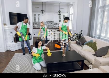 Multiracial cleaners using modern tools for tidying up room Stock Photo