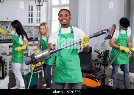 Smiling african man, cleaning service worker, holding vacuum cleaner