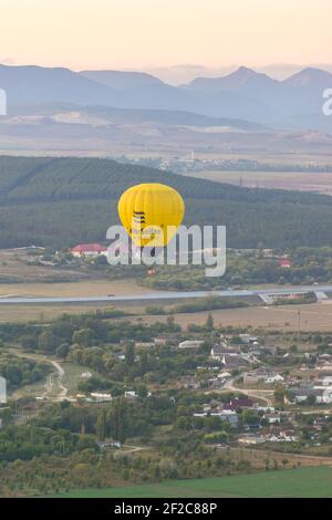 Russia, Crimea, Belogorsk September 19, 2020-A yellow balloon with the GelbeSeiten logo flies over the village of Belaya Skala at the foot of the moun Stock Photo