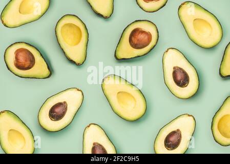 fresh ripe avocados pattern on a green background Stock Photo