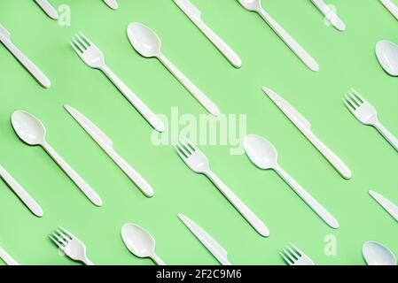 Geometric pattern made with white plastic cutlery on a green background Stock Photo