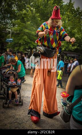 05-2016 Muskogge USA Clown on stilts blows bubbles among crowd Stock Photo