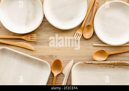 Set of dry biodegradable empty new palm leaf plates and edible fork, knife, spoon and bamboo straw border. Room for text in the middle. Stock Photo