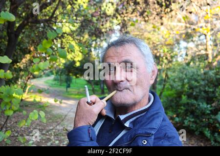 1-3-2018 Athens Greece Older Armenian Man smoking a pipe in the park - funny face Stock Photo