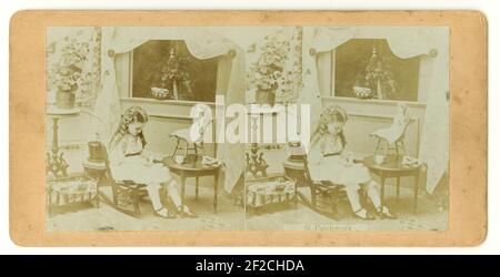 Original Victorian stereographic image of young girl sitting in her bedroom with doll, sewing - captioned  'patchwork',  circa 1860's U.K Stock Photo