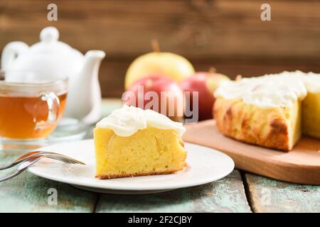Traditional English cake with apples and whipped cream served with tea on blue wooden background closeup Stock Photo