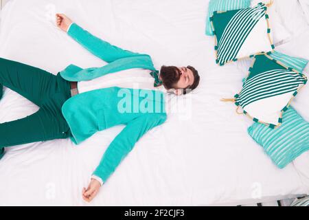 Drained physical and mental resources. One more long day ended. Feel tired and sleepy. Sleepy guy in formal clothes sleep on bed. Lack of sleep. Need more sleep. Evening time. Businessman exhausted. Stock Photo