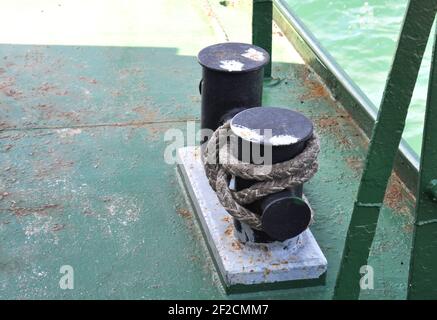 Rusty mooring post with ship ropes on an old ferry. Bollard with mooring lines on the ship. Stock Photo