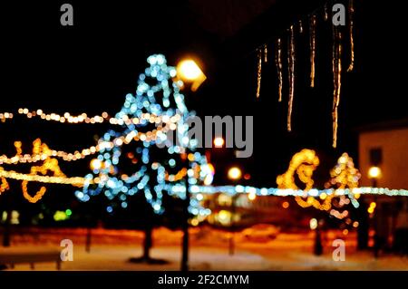 Picture of hanging icicles at night with blurred Christmas decoration in the background Stock Photo