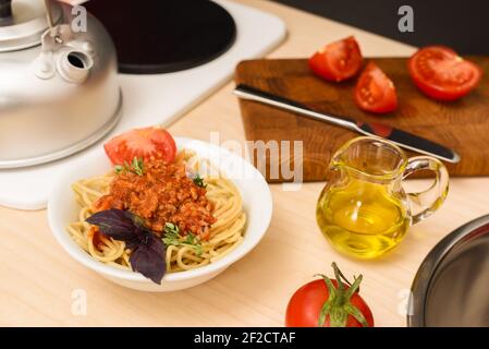 Spaghetti bolognese with olive oil, tomatoes and basil in toy kitchen closeup Stock Photo