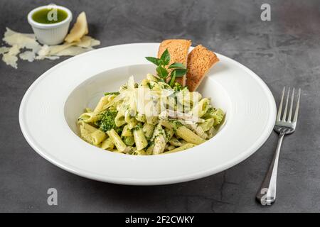 Penne pasta with pesto sauce, zucchini, green peas and basil. Stock Photo
