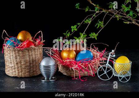 Homemade multicolored painted Easter eggs on colorful straw in wicker baskets and in stands on a dark background, Easter decoration Stock Photo