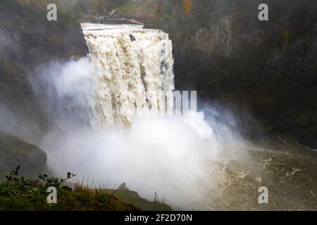 Water thunders over Snoqualmie Falls after heavy rains creating spray in King County Washington State due to heavy rainfall in the Cascade Mountains Stock Photo