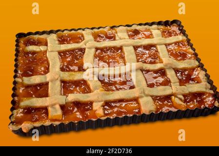 Rustic pie tart with jam, typical homemade Italian cake in baking tray isolated on orange background Stock Photo