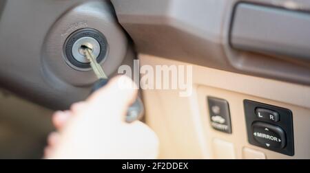 Close up the female hand use the car key into the keyhold preparing to start a car. Stock Photo