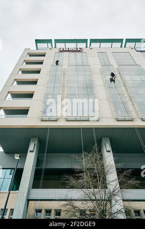 Window washer cleaning the outside windows of a high rise building from a low angle, in Montgomery Alabama, USA. Stock Photo