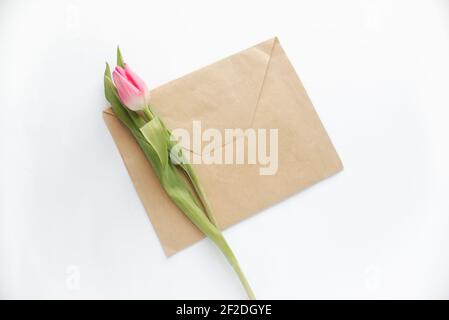 envelope from craft brown paper and pink tulip flower on white paper background Stock Photo
