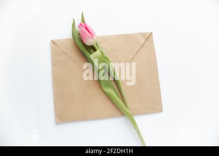 envelope from craft brown paper and pink tulip flower on white paper background Stock Photo