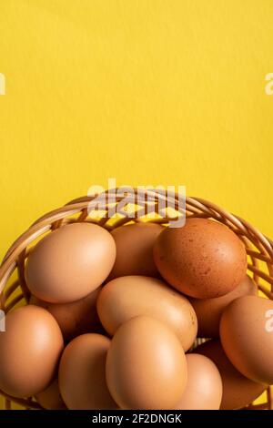 Top view on fresh organic eggs in basket on the yellow background Stock Photo
