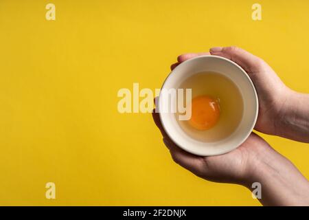 Top view fresh organic eggs in hands holding above yellow background Stock Photo