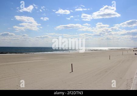 Sun Shining on Shoreline with a lightly cloudy but crisp blue sky Stock Photo