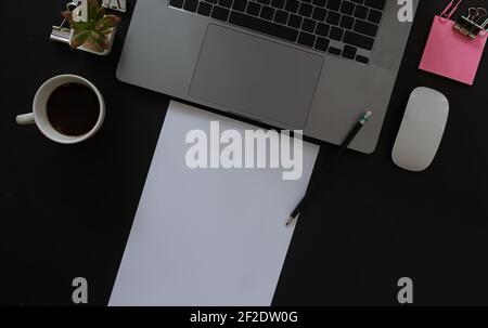 Business desk with laptop and memo paper placed on a black background, including a copy area to add text or graphics. Stock Photo