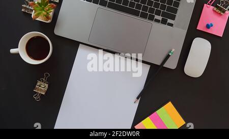 Business desk with laptop and memo paper placed on a black background, including a copy area to add text or graphics. Stock Photo