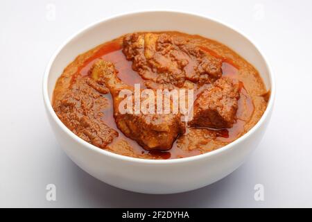 Chicken curry or masala , spicy chicken curry made using fried coconut in traditional way,arranged in a white ceramic bowl with white background,isola