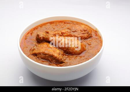 Chicken curry or masala , spicy chicken curry made using fried coconut in traditional way,arranged in a white ceramic bowl with white background,isola