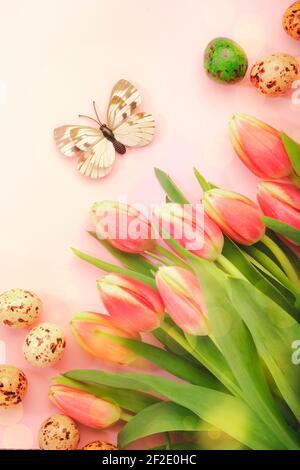 Spring Easter holiday pink background with tulips, quail eggs, butterflies. Top view Stock Photo