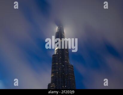 Burj Khalifa at night with the top covered by low clouds. Skyscraper in Dubai, United Arab Emirates. Highrise top behind cloud. Stock Photo