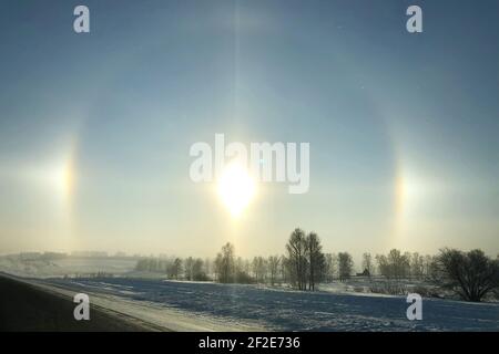 Halo effect over the frozen winter forest, view from the country road. Magical unbelievable nature phenomenon Stock Photo