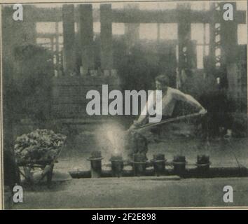Pouring molten metal from the crucible pot into the ingot moulds, (HS85-10-32646). Stock Photo