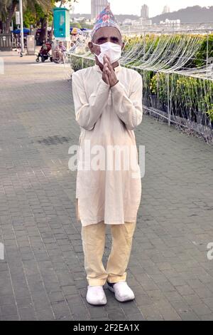 Nepal senior man wearing traditional Daura Suruwal clothes and Dhaka Topi hat and welcoming with the Namaste greeting of clasped hands. Stock Photo