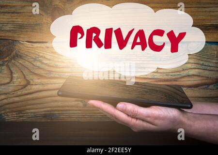PRIVACY concept. Tablet computer in a woman's hands on a wooden background. Stock Photo
