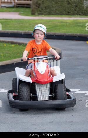 A young boy riding an electric quad bike around an outdoor track Stock Photo