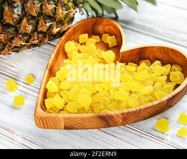Sweet pineapple succade cubes on white wooden background Stock Photo